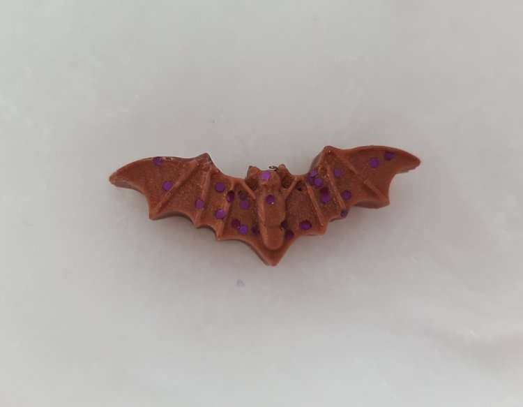 Brown bat-shaped wax melt with purple glitter for Halloween ambiance.