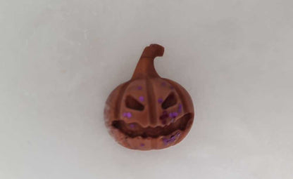 Halloween pumpkin-shaped wax melt with brown color and purple glitter.