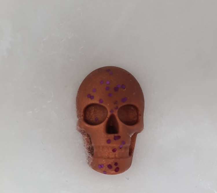 Skull-shaped Halloween wax melt with brown and purple glitter.