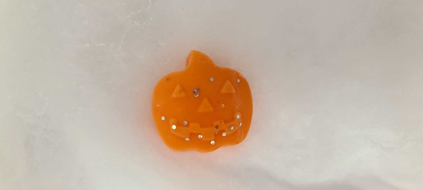 Pumpkin-shaped spiced wax melt with decorative design on a white surface.